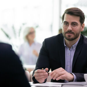 Pensive confident young male CEO or director talk speak with business partner or client at meeting in office. Successful Caucasian businessman brainstorm cooperate with colleague at briefing.